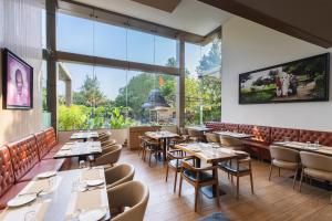 a restaurant with tables and chairs and large windows at Temple Tree Hotel Shirdi, a member of Radisson Individuals in Shirdi