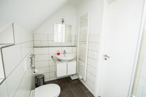 a white bathroom with a toilet and a sink at Murthum Apartments in Leinfelden-Echterdingen +23 photos