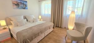 a white bedroom with a bed and a chair at Lake&Mountain Apartments in Andechs