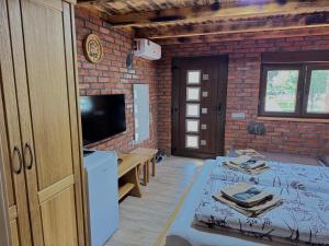 a room with a bed and a tv and a brick wall at Etno Camp Lucić in Odžak