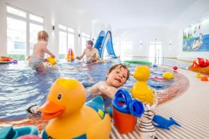 a young child playing in a swimming pool with toy ducks at Familotel Borchards Rookhus in Wesenberg