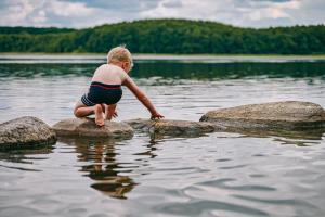 a young boy stepping on rocks in a body of water at Familotel Borchards Rookhus in Wesenberg