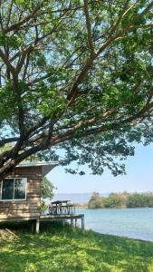 a cabin with a picnic table next to a lake at บ้านสวนริมอ่าง in Phayao