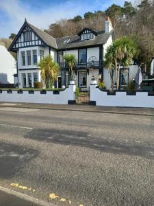 a house with palm trees on the side of the street at Battery Lodge in Rothesay