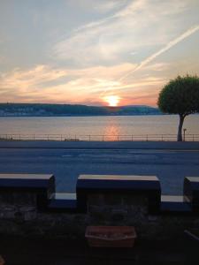 a sunset over a body of water with two benches at Battery Lodge in Rothesay