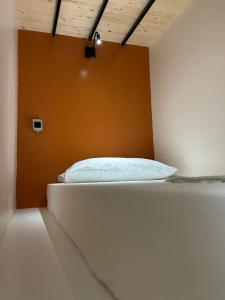 a white bed in a room with an orange wall at Queen-V Hostel in Vlorë