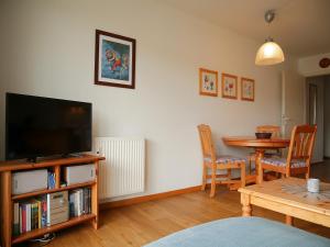 a living room with a flat screen tv and a table at Tschach in Kirchdorf
