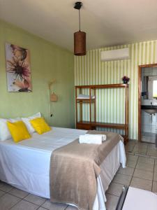 a bedroom with a large white bed with yellow pillows at Pequena Sereia Guriri in São Mateus