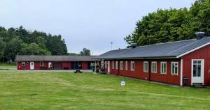 a red barn with a large grass field next to it at Degeberga Stugby in Degeberga +11 photos