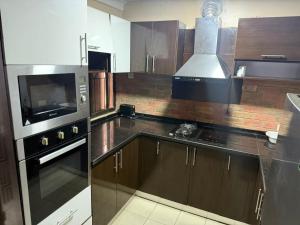 a kitchen with wooden cabinets and a stove top oven at NO 95 Suites LEKKI PHASE 1 in Ilado