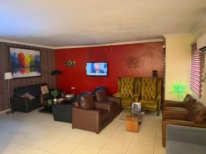 a living room with leather furniture and a red wall at NO 95 Suites LEKKI PHASE 1 in Ilado