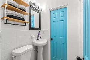 a blue door in a bathroom with a toilet and a sink at Surf Drive - Ultimate Beach Getaway for Families in Cocoa Beach +72 photos