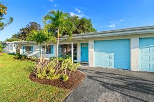 a house with blue garage doors and palm trees at Surf Drive - Ultimate Beach Getaway for Families in Cocoa Beach