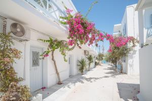 a street with pink flowers on a white building at Hotel Mantalena in Antiparos