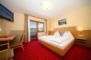 a hotel room with a bed and a desk and a television at Pension Spreitzhof & Appartement Royer in Schladming