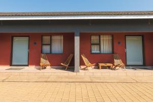 three chairs and a table in front of a building at Trig Beacon in Manzini