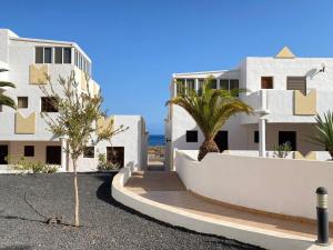 a white building with palm trees in front of it at Casa Candy. Piscina, Mar y Paz. in Tuineje