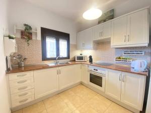 a kitchen with white cabinets and a sink and a window at Casa Candy. Piscina, Mar y Paz. in Tuineje