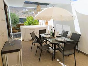 a table with chairs and an umbrella on a patio at Villa Majada Del Aceitun in Gran Tarajal