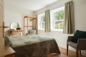 a bedroom with a bed and a chair and two windows at Quayside Apartments, Brixham in Brixham +50 photos
