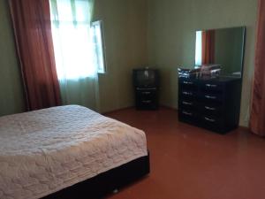 a bedroom with a bed and a dresser and a mirror at Aisi in Stantsiya Sagaredzho