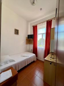 a room with two beds and a window with red curtains at Sinziana Eforie Sud in Eforie Sud +4 photos