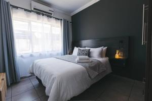 a bedroom with a bed with white sheets and a window at Trig Beacon in Manzini