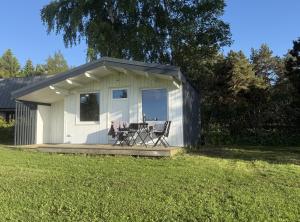 a small white shed with a table on a deck at Rävboet in Österbi