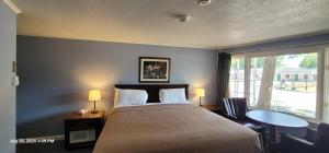 a bedroom with a bed and a table and a window at The Tallwood Motel in Wells +44 photos