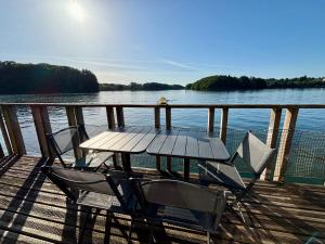 a wooden deck with a table and chairs on the water at Chalets flottants lac de Saint Étienne Cantalès in Saint-Gérons