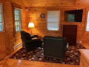 a living room with two chairs and a television at Rivers Edge Cabins - Tranquil Nook in Cushing