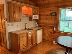 a kitchen with wooden cabinets and a table in a cabin at Rivers Edge Cabins - Tranquil Nook in Cushing