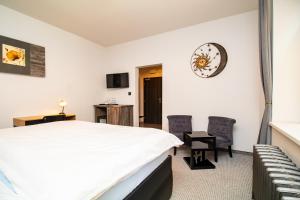 ein Schlafzimmer mit einem Bett, zwei Stühlen und einer Uhr in der Unterkunft Padre Boutique Hotel in Ostrava