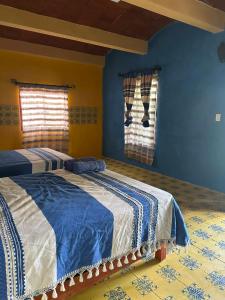 a bedroom with two beds and blue walls and a window at Ojo de Luna Teotitlan in Teotitlán del Valle