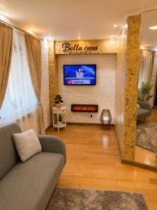 a living room with a couch and a tv on a wall at Bella Casa Apartments in Făgăraş
