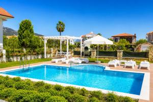 a pool with chairs and umbrellas next to a house at Villa Portakal Blossom in Dalyan