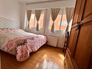 a bedroom with a bed and two windows at HOSTAL MATILDAs in Segovia