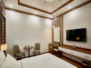 a bedroom with a bed and a tv and a table at NEW SUN NAM ĐỊNH hotel in Nam Ðịnh