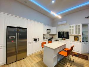 a kitchen with white cabinets and a kitchen island with orange chairs at Göl Konuk Evi in Sakarya