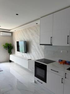 a kitchen with white cabinets and a tv on a wall at Bellanti2 in Igalo