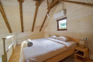 a bed in a wooden room with a window at Golubek Holiday House in Banščica