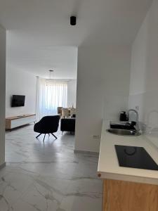 a white kitchen with a sink and a living room at Morea Residence in Ulcinj