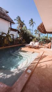 a swimming pool next to a house with palm trees at Villa Upendo with Private Pool and Ocean View Zanzibar in Pingwe
