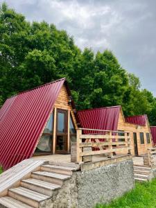 a log cabin with a red roof and a wooden deck at Shahunts Resort in Odzun