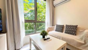 a living room with a couch and a table and a window at Peaceful Fantasia Condo Kamala in Surin Beach