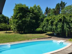 a blue swimming pool in a yard with trees at La Canette de Phil - Chambre d'hôtes, Indépendante - Vue sur piscine in Samatan