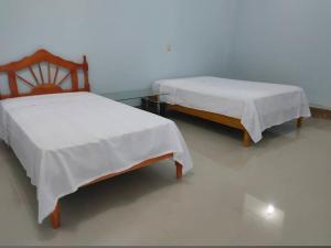 two beds sitting next to each other in a room at Hostal El Bosque in Pedernales