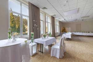 une salle de banquet avec des tables blanches et des chaises blanches dans l'établissement Impresja Art Resort, à Duszniki-Zdrój