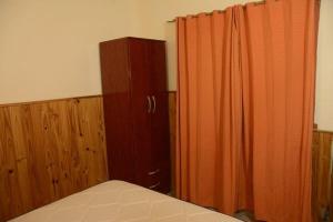 a bedroom with an orange curtain and a bed at Las Grutas Centro alojamiento in Las Grutas