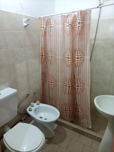 a bathroom with a toilet and a shower curtain at Las Grutas Centro alojamiento in Las Grutas